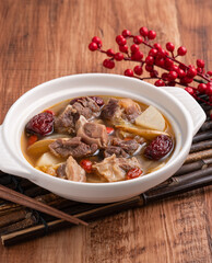 Traditional Chinese medicinal mutton hot pot with herbs in white bowl.