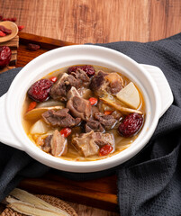 Traditional Chinese medicinal mutton hot pot with herbs in white bowl.
