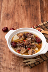 Traditional Chinese medicinal mutton hot pot with herbs in white bowl.
