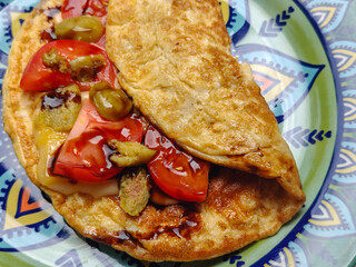 Breakfast. Omelet with tomatoes, olives, and teriyaki sauce on green, colorful plate on the light marble table. Healthy breakfast. Part of the series. Top view. Close-up