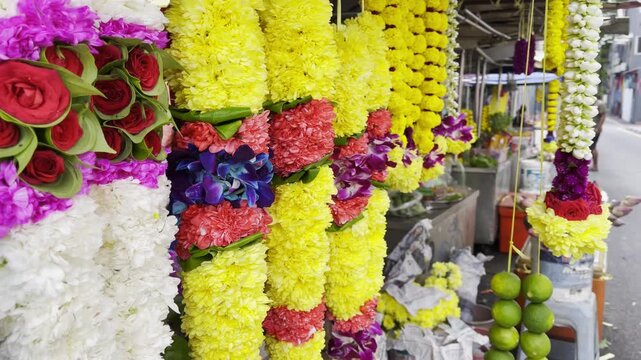 Bright flower garlands made of roses, chrysanthemums, jasmine, orchids, and limes hang at a stall in Little India, Kuala Lumpur, showcasing the vibrant colors of Indian cultural traditions