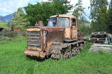 An old abandoned Soviet tractor overgrown with grass