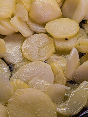 Detailed view of potato slices cooking in hot water or oil, creating a rich texture.