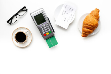 Bank card payment POS terminal. Paying the bill at a restaurant. Cup of black coffee with the bill on white table.