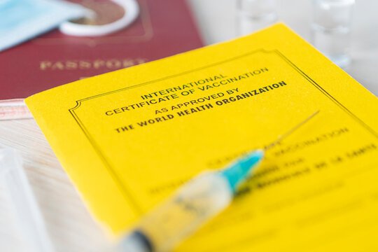 international certificate of vaccination a document for recording the vaccines made. the document is a yellow color. passport of a foreign citizen and a syringe on table. concept of safe travel. - Powered by Adobe