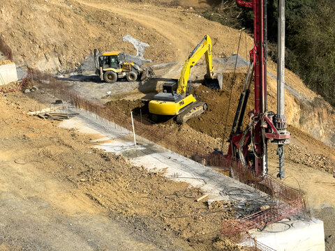View of construction machinery in action, with an excavator digging and a drilling machine boring into the earth, amidst a landscape of soil and concrete, Istanbul, Istanbul, Turkey.