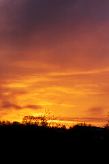 Dramatic golden sunrise sky with vivid orange clouds above dark silhouettes