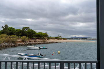 Scenic view of boats, beach, and trees under a cloudy sky in Portugal