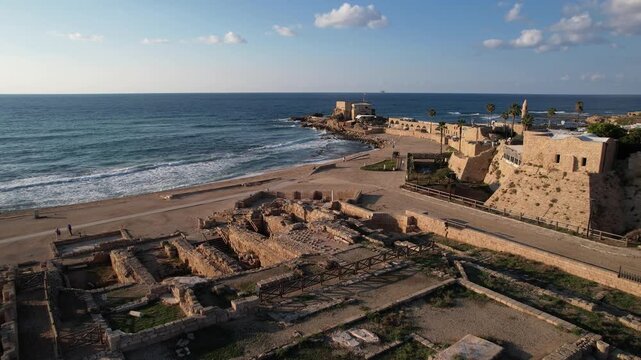 Rising drone shot over Caesarea National Park in Israel, revealing ancient Roman ruins, beach shoreline, and Mediterranean Sea under clear coastal light.