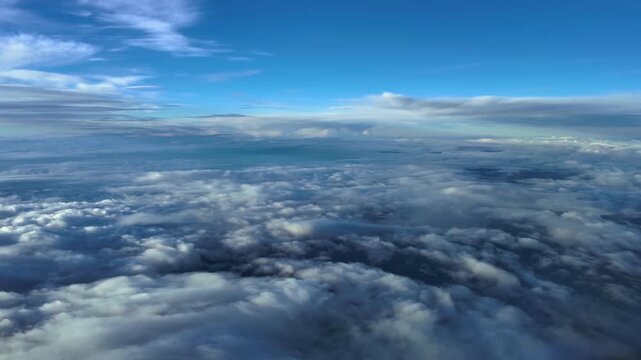 Fighter jet cokpit perspective in a supersonic flight over multilayered broken clouds under a deep blue sky.