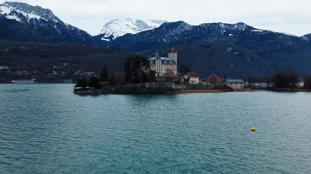 Aerial view of the Chateau de Duingt, a medieval castle, perched on a small island surrounded by the tranquil waters and snow capped mountains, Duingt, Auvergne-Rhone-Alpes, France.