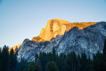 Majestic Half Dome Peak in Yosemite National Park Illuminated by Golden Sunrise Light Against a Clear Blue Sky