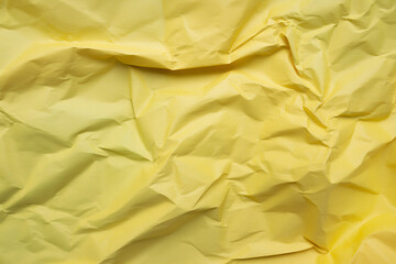 Closeup view of a vibrant yellow crumpled paper texture, showcasing its intricate folds and creases