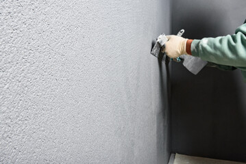 Applying concrete pebble plaster kornik using putty knife.
