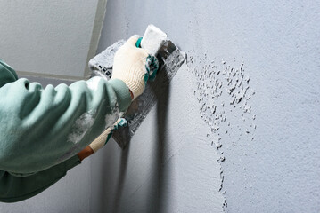 Applying concrete pebble plaster kornik using putty knife.