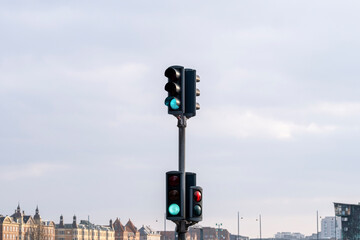 An image of two traffic light systems showing green and red signals against a cloudy sky, representing navigation and communication in city settings.
