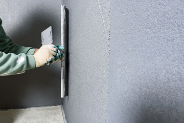 Applying concrete pebble plaster kornik using putty knife.