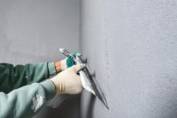 Applying concrete pebble plaster kornik using putty knife.