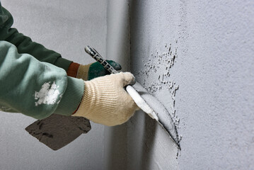 Applying concrete pebble plaster kornik using putty knife.