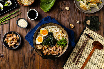 Traditional ramen with jerked pork or chicken.  With udon or ramen noodles. Served in classic bowls. Gyoza dumplings and mushrooms in the background.