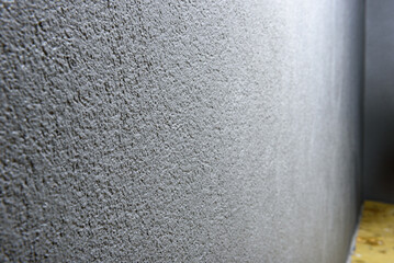 Applying gray concrete pebble plaster kornik on the wall.
