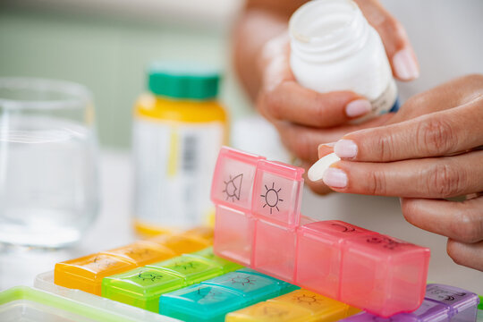 Medication adherence. Preparing a pill box to manage her medication schedule. Shows clear sorting, controlled dose planning, and steady health organization.