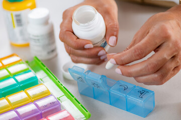 Medication adherence. Filling weekly pill compartments to simplify daily intake. Highlights precise sorting, organized structure, and responsible medication management.