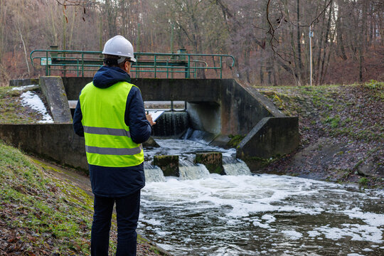 Environmental engineer checking water flow near a hydro dam. Biologist analyzes water quality and chemical composition for resource monitoring. Testing the chemical flow rate for environmental control