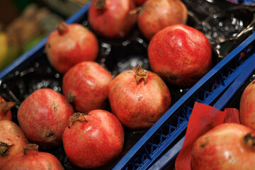 Fresh pomegranates arranged in market crates, showcasing their vibrant red color and natural textured skin.