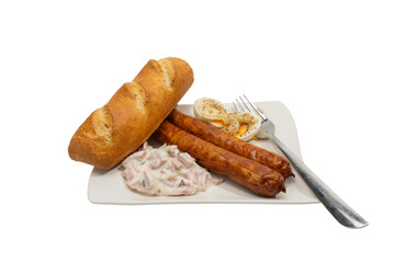 Fried bratwurst with baguette, egg halves, and creamy salad on a white plate. Isolated on white,...