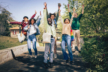 Obraz premium Group of diverse young friends jumping outdoors celebrating together in a joyful moment
