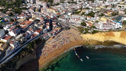 Scenic Aerial Drone Shot of Praia do Carvoeiro’s Colorful Seaside Village and Majestic Algarve Cliffs Overlooking the Bright Blue Atlantic Ocean