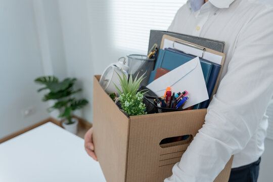 Stressful businessmen will resign from the company. lifting a brown paper box that holds personal items. resignation, job placement and vacancies concept. - Powered by Adobe