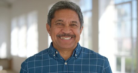 Face of a happy retired man inside a bright room. Portrait of a senior man in a retirement home with a cheerful expression. Modern man looking joyful and smiling while enjoying his leisure indoors