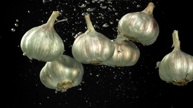 The heads of fresh garlic fall under the water. Filmed on a high-speed camera at 1000 fps. High quality FullHD footage