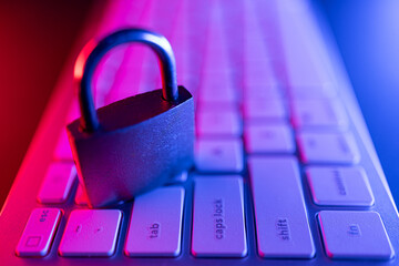 Security lock on keyboard in cyber security setting with colorful lighting at night