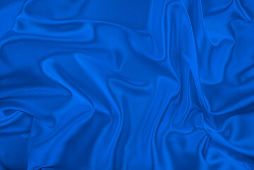 A luxurious, deep cobalt blue satin fabric is draped and wrinkled, creating a beautiful texture and...