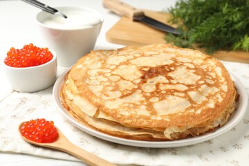 Tasty crepes with red caviar, sour cream and dill on table, closeup