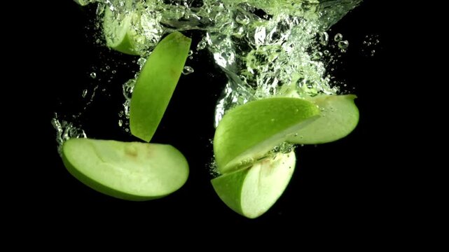 Pieces of green apples fall under the water. Filmed on a high-speed camera at 1000 fps. High quality FullHD footage