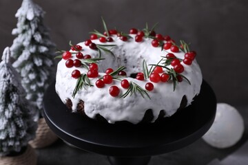 Tasty Christmas cake with cranberries, rosemary and festive decor on table, closeup