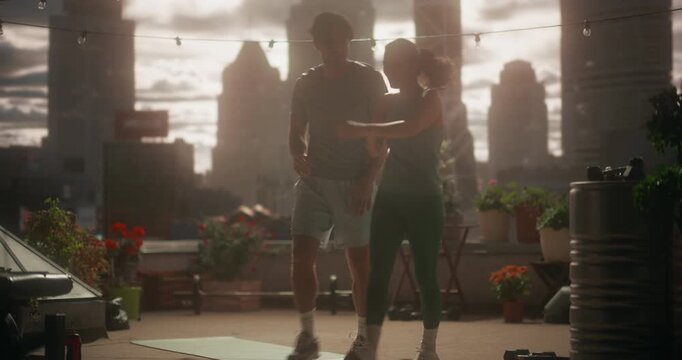 Smiling Man and Beautiful Woman Complete a Rooftop Cardio Workout, Giving a High Five after Successul Workout and Support Each Other&rsquo;s Fitness Routine with City View