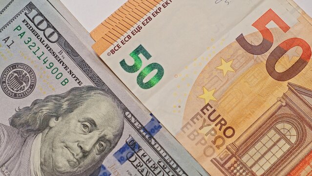 Closeup of a US hundred dollar bill and euro fifty banknote overlapping, symbolizing global finance, currency exchange, money transfer, and international economic relations.