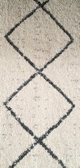 Obraz premium The texture of a white carpet with a pattern of simple black broken and intersecting lines. Carpets for home decor, wallpaper, textiles, and fashion.