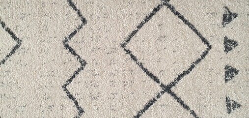 The texture of a white carpet with a pattern of simple black broken and intersecting lines. Carpets for home decor, wallpaper, textiles, and fashion.