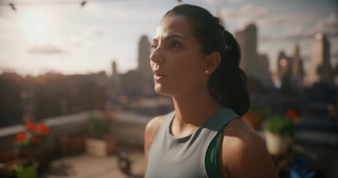 Young Woman Pauses on a Rooftop Workout Area, Taking Slow Deep Breaths After Cardio Exercise, Using Outdoor Training to Support Everyday Fitness, Heart Health