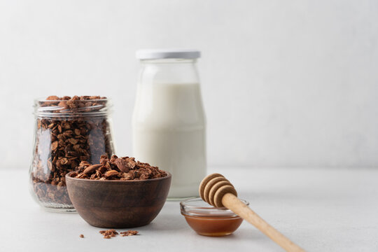 Chocolate granola with almonds in a wooden bowl close-up view on white background with copy space. Healthy breakfast concept