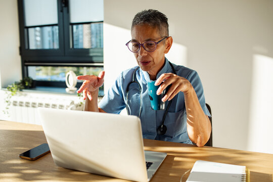 Mature doctor having focused video call at home office