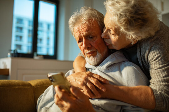 Senior couple comforting on home sofa, worried over phone