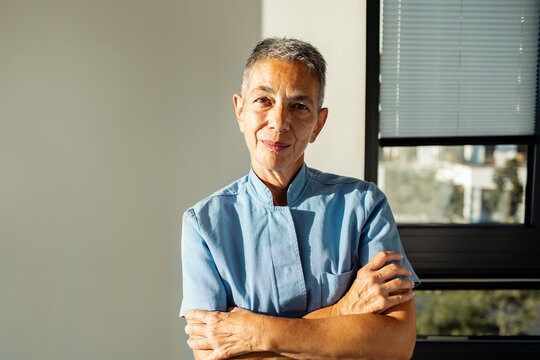 Senior woman in uniform smiling confidently by office window