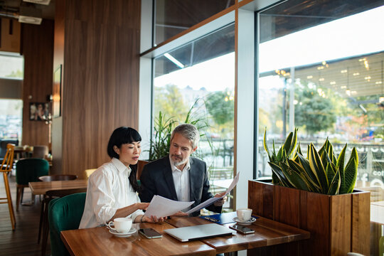 Adult woman and mature man in focused business meeting at cafe